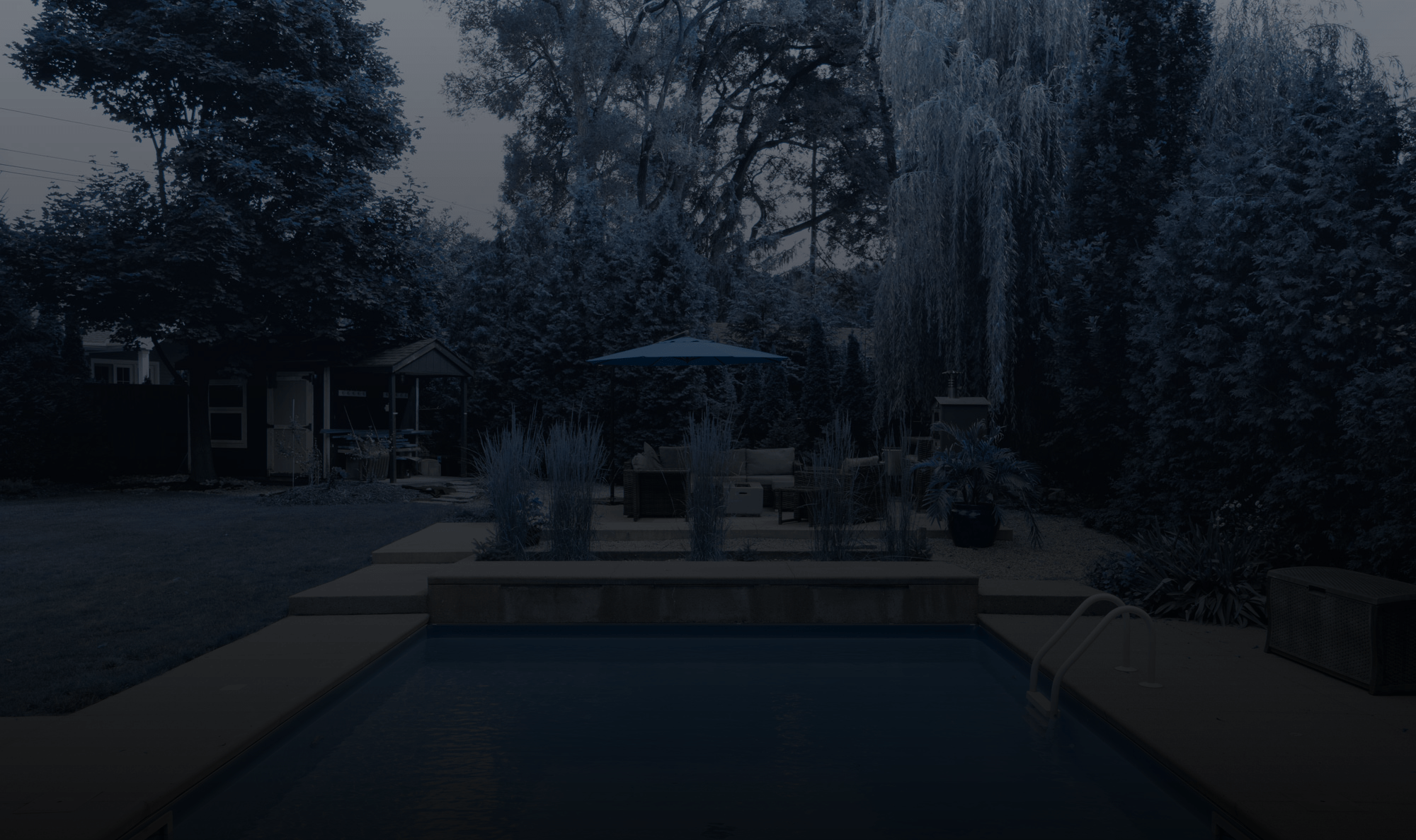 A serene backyard features a pool, seating area, and lush trees, creating a tranquil outdoor retreat under natural shade. No landmarks visible.