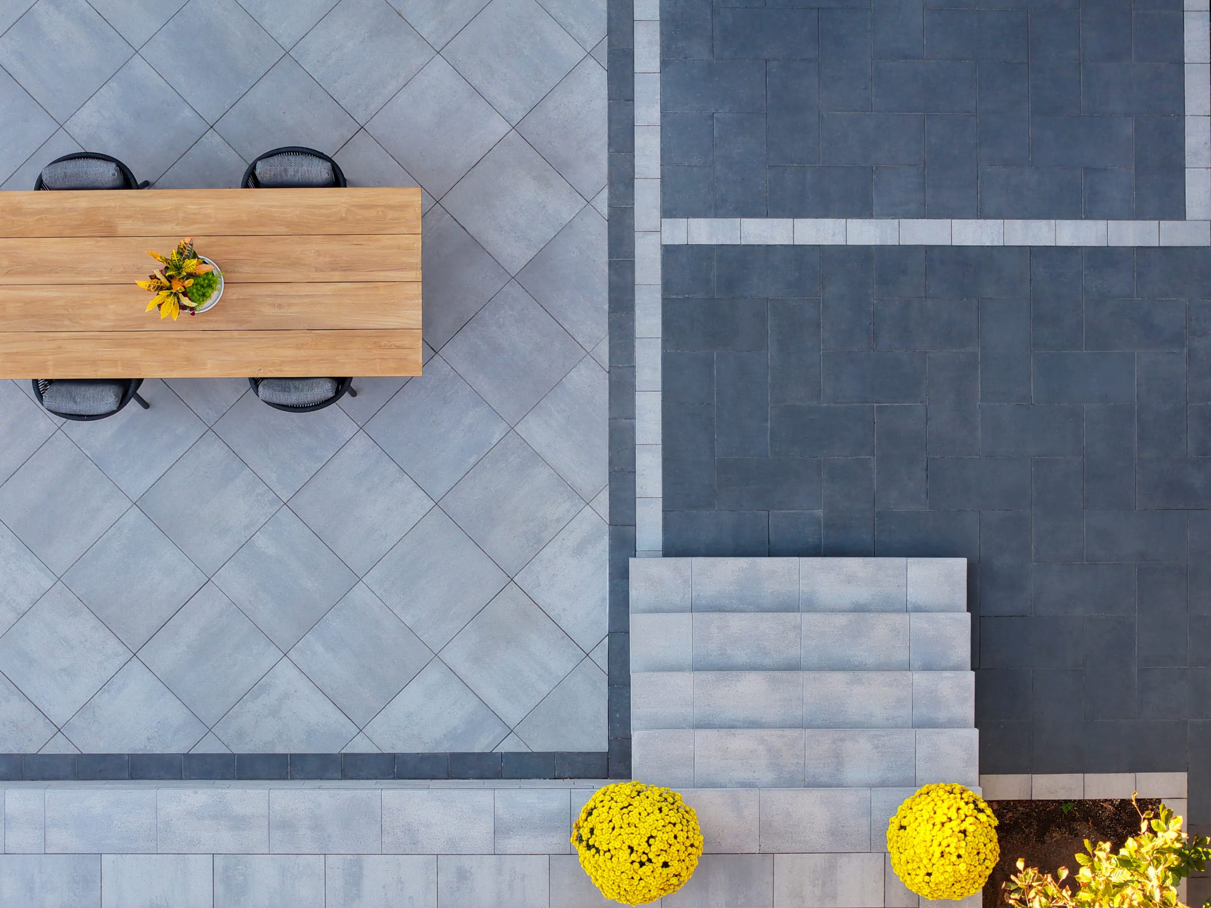 Overhead view of a geometric patio layout showing the contrast between light grey Cloudburst pavers and dark charcoal borders.