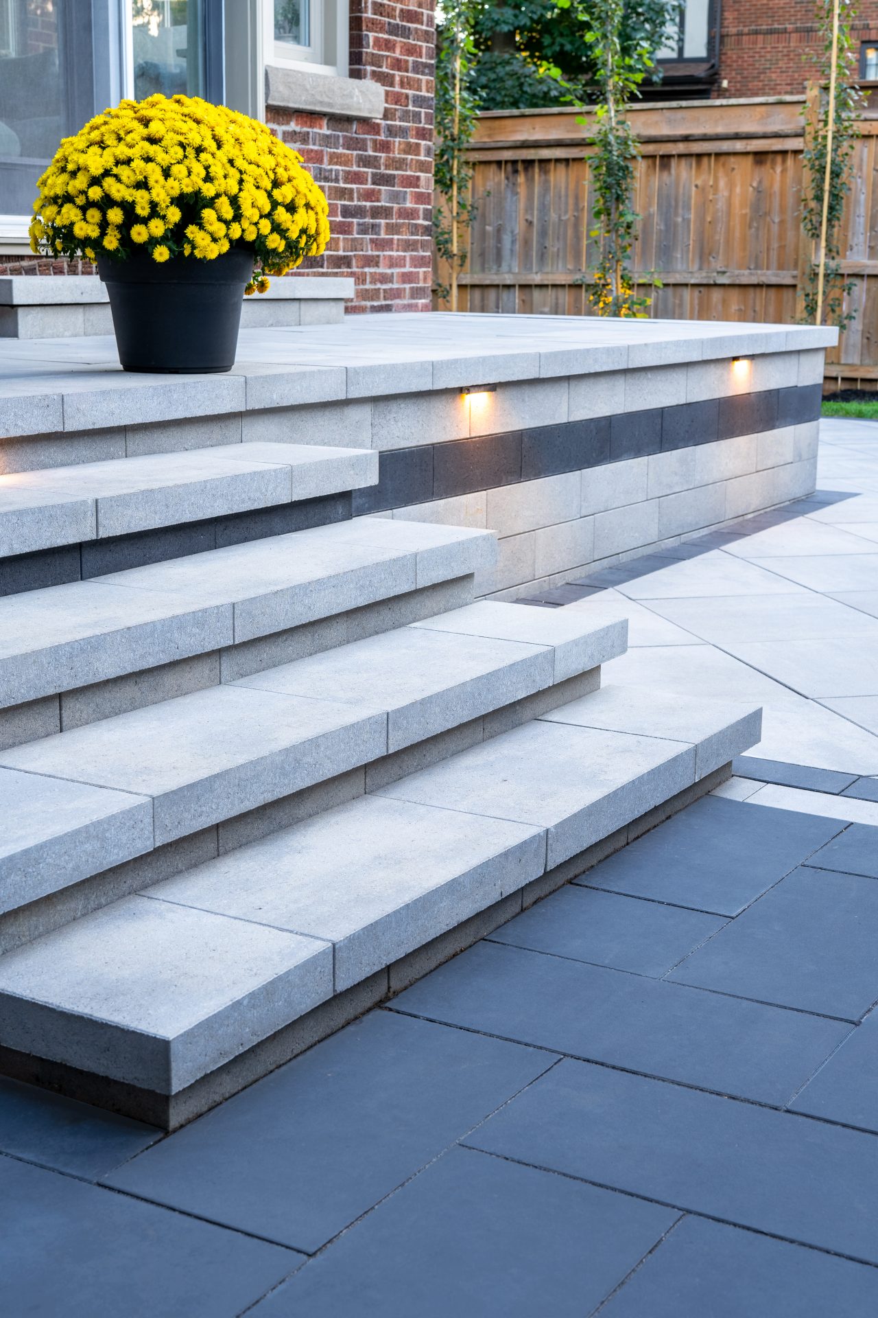 Close-up of Nueva stone steps in Cloudburst with a dark accent stripe and warm built-in LED lighting for safety and ambiance.